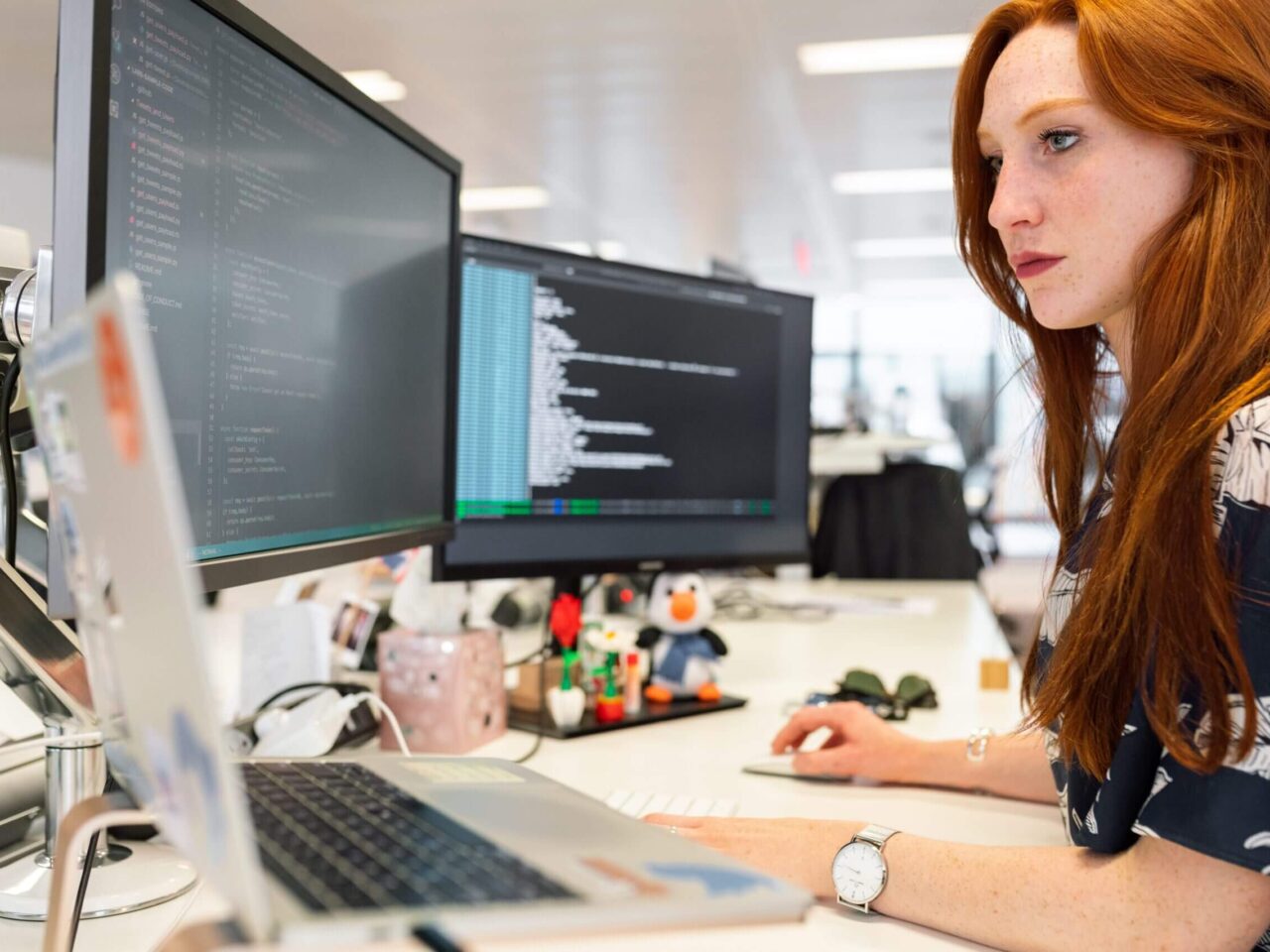 Frau arbeitet an der Implementierung von SAP SuccessFactors LMS auf mehreren Bildschirmen im Büro.