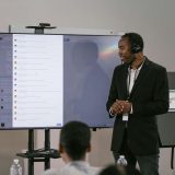 Trainer präsentiert digitales Trainingsmanagement für SAP S/4HANA vor interaktivem Bildschirm