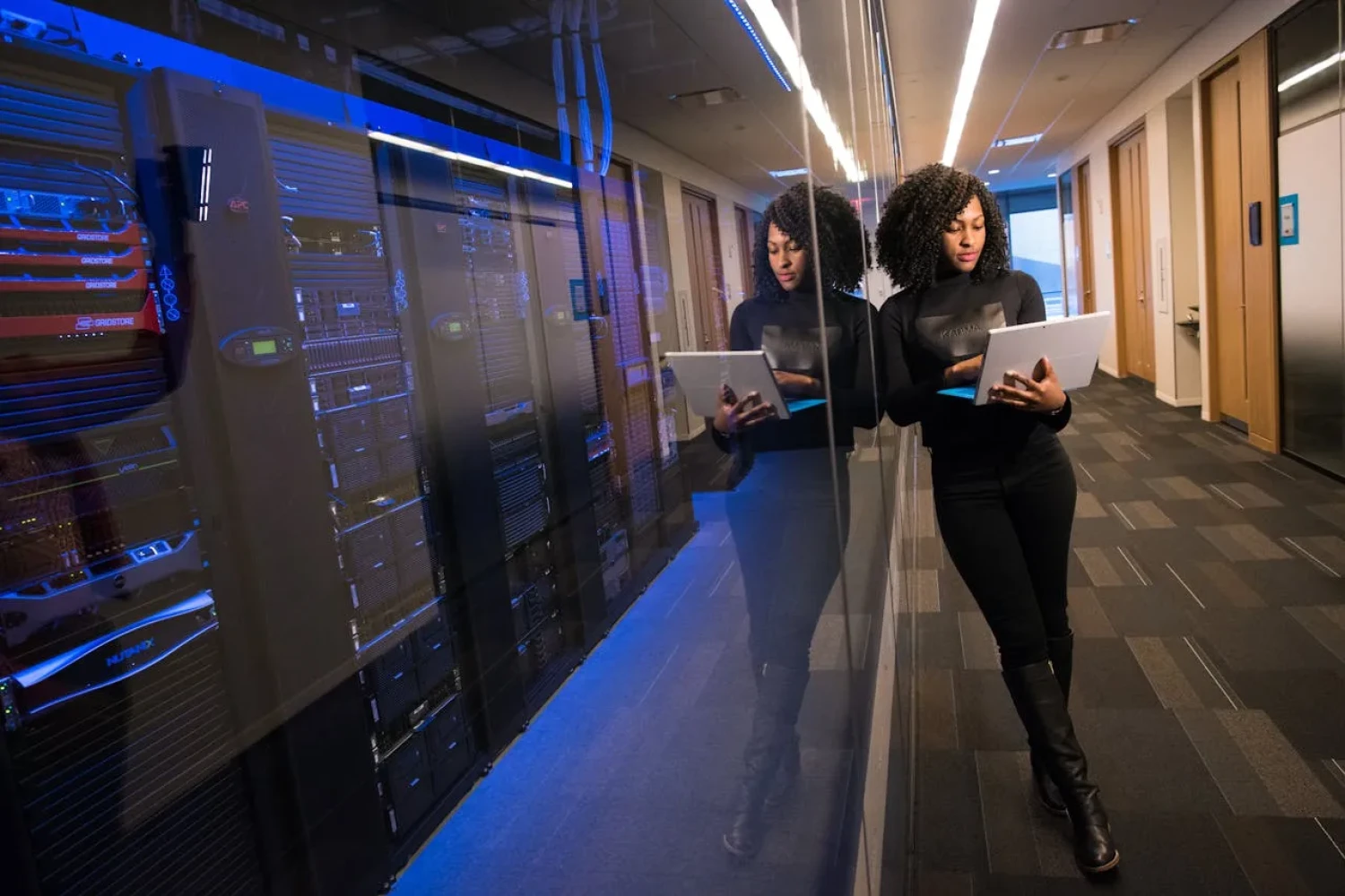 Frau mit Tablet im Serverraum – professionelles LMS Hosting und digitale Weiterbildung