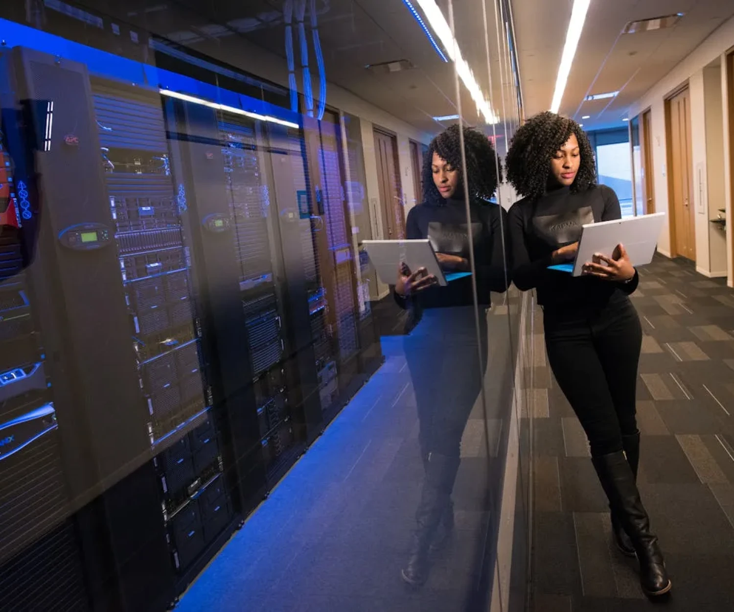 Frau mit Tablet im Serverraum – professionelles LMS Hosting und digitale Weiterbildung