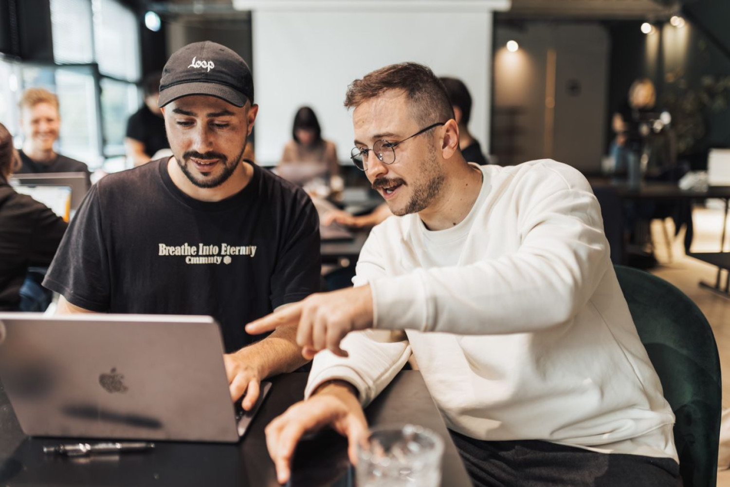 Zwei Kollegen vergleichen am Laptop Moodle oder SaaS-LMS für ihre Organisation