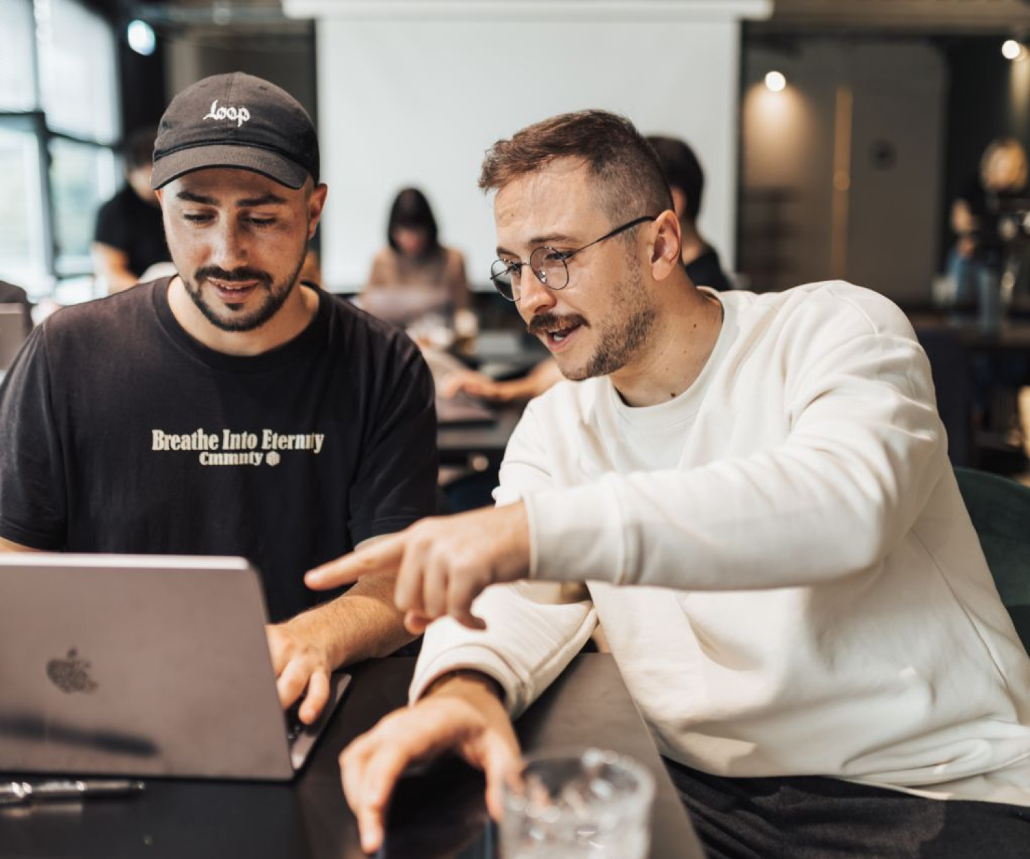 Zwei Kollegen vergleichen am Laptop Moodle oder SaaS-LMS für ihre Organisation